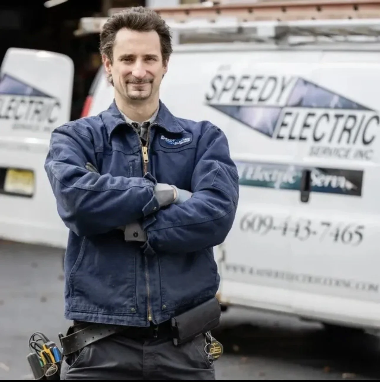 Mr. Speedy Electric technician standing in front of a branded service van